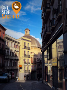 Vibrant and sunny street view of Via Manno in Cagliari, lined with shops, cafés, and charming architecture.