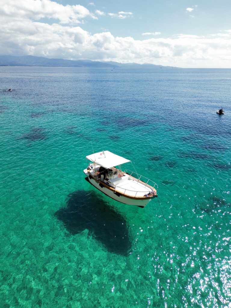 Panoramic view of Sardinia’s turquoise sea with sailboats in the distance – a highlight of La Dolce Vita Tour.